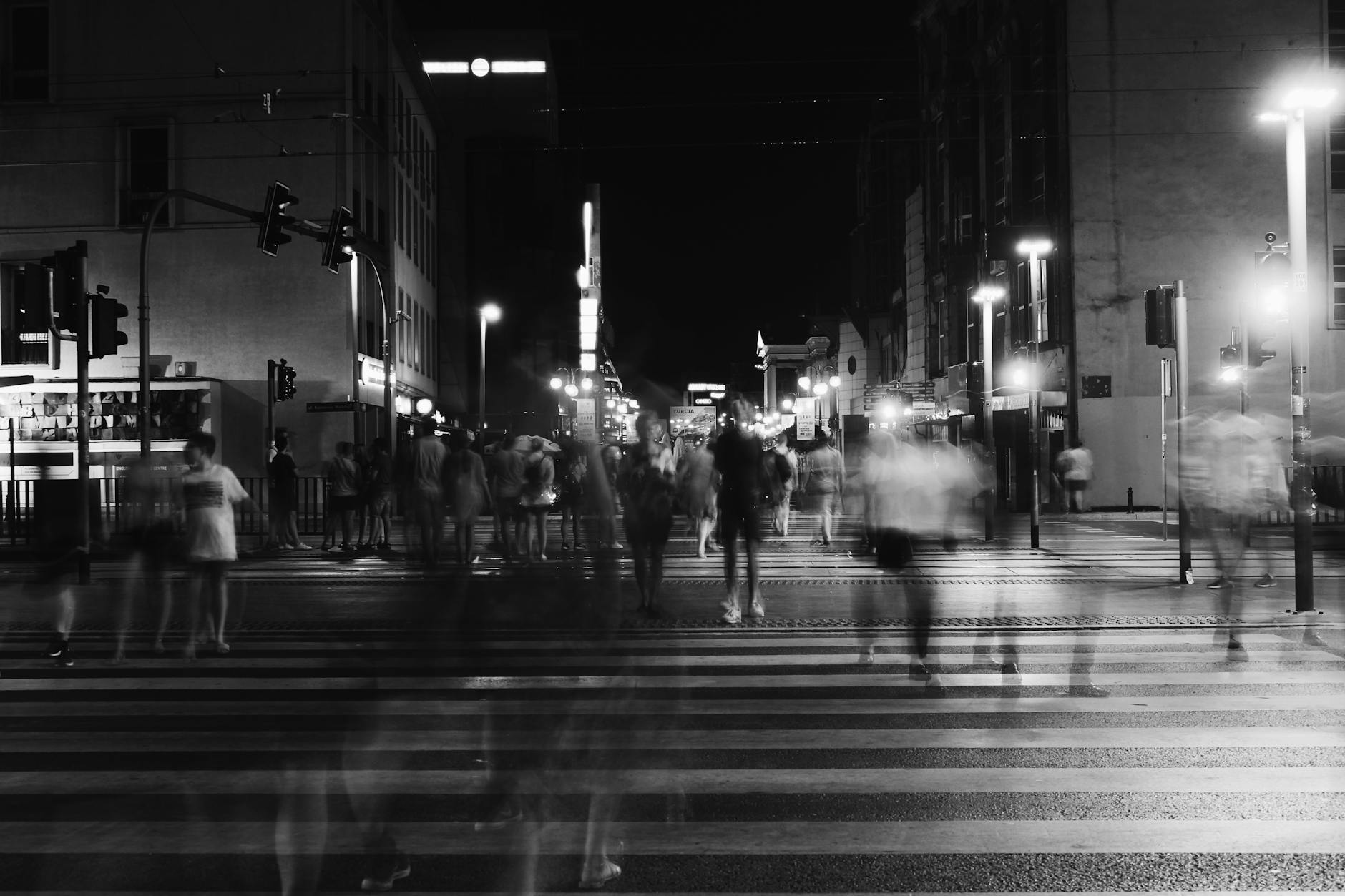 group of people crossing pedestrian lane in greyscale