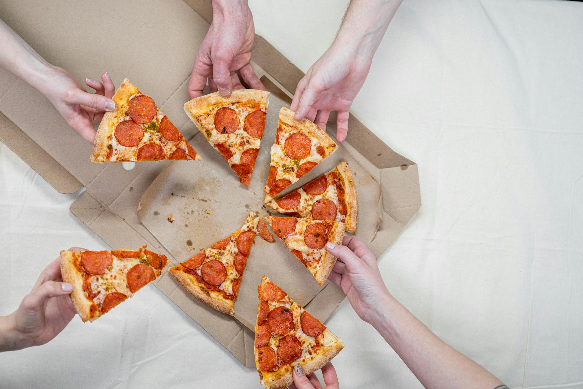 photo of people holding pizza Photo by cottonbro studio on Pexels.com